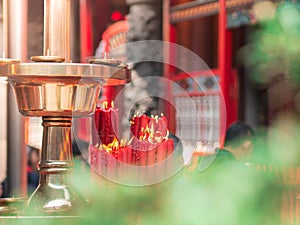 Closeup bundle of big red candles burning near the golden tray at Longshan temple.