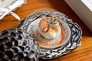 Closeup of Burrata cheese covered in red pepper powder and decorated with tomato sepals