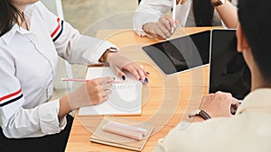 Closeup business developer group talking/meeting/discussing together while sitting at wooden working desk.