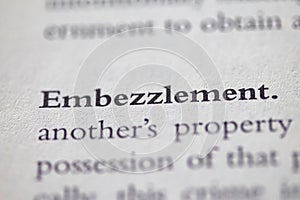 Closeup of Business legal term Embezzlement printed in textbook on white page.