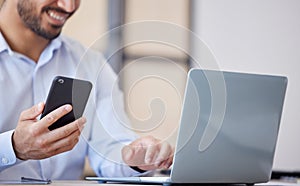 Closeup of business man using smartphone and laptop in office. Man using mobile phone app for synchronizing data with