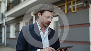 Closeup business man using tablet at street. Man working on touchpad outdoors