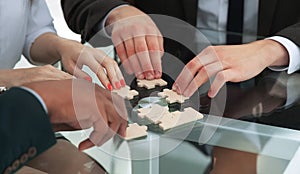 Closeup .business team assembling puzzle sitting behind a Desk