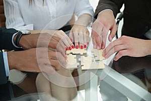 Closeup .business team assembling puzzle sitting behind a Desk