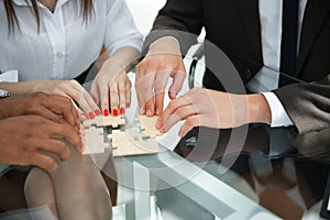 Closeup .business team assembling puzzle sitting behind a Desk