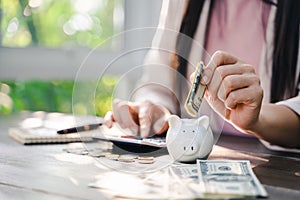 Closeup of business woman hand putting money coin into piggy bank for saving money. saving money and financial concept