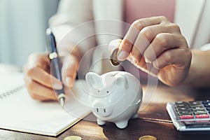 Closeup of business woman hand putting money coin into piggy bank for saving money. saving money and financial concept