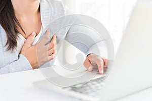 Closeup business woman having heart attack. Woman touching breast and having chest pain after long hours work on computer. Office