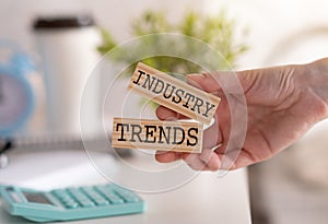 Closeup on business woman holding a wooden block with Industry trends message, business concept