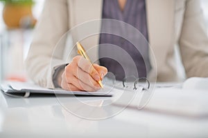 Closeup on business woman writing in document