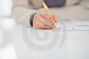 Closeup on business woman writing in document