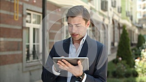 Closeup businessman browsing internet outdoors. Man holding touchpad at street