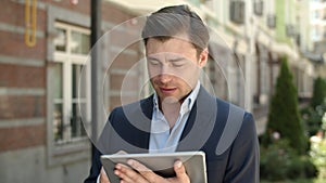 Closeup businessman browsing internet outdoors. Man holding touchpad at street