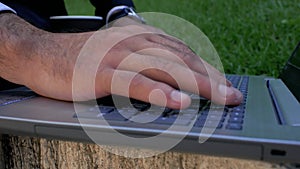 Closeup of businessman hand typing on laptop keyboard. man using laptop in park. concept of network communications. freelance