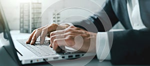 Closeup of businessman hands typing on laptop computer in office. banner