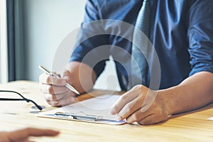 Closeup businessman hands working on finance business document reading report paperwork spreadsheet using laptop at office desk.