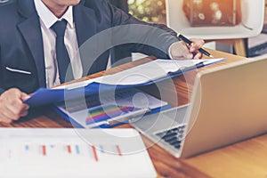 Closeup businessman hands working use laptop finance business document reading report paperwork spreadsheet at office desk. Man