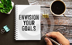 Closeup on businessman holding a card with text ENVISION YOUR GOALS