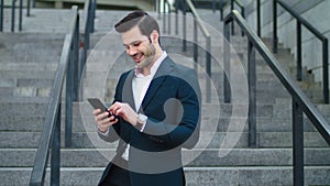 Closeup businessman laughing at street. Man using modern smartphone outside