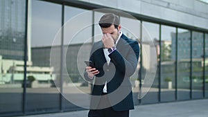 Closeup businessman reading bad news at street. Businessman using smartphone