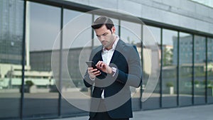 Closeup businessman reading bad news at street. Businessman using smartphone