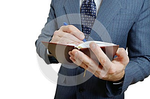 Closeup of a businessman taking notes in a small notebook.