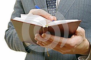 Closeup of a businessman taking notes in a small notebook.