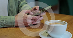 Closeup businessman typing message on mobile phone at cafe. Close up man hands using smartphone.