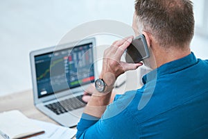 Closeup of a businessman using a phone and laptop, trading on the stock market in a financial crisis. Online trader with