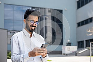 Closeup businessman walking city and using application on smartphone, a smiling Hispanic man holding a phone in his