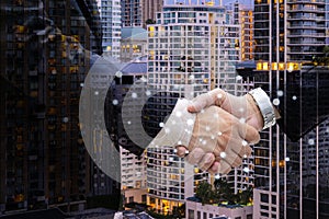 Closeup businessmen shaking hands on background modern office corporate buildings. Success and Happiness concept