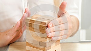 Closeup of businesswoman building high tower with wooden toy blocks and bricks. Concept of development, success and