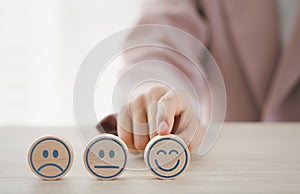 Closeup businesswoman finger pointing on happy emotion face on wooden piece arranged on table for satisfaction survey