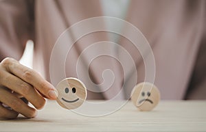 Closeup businesswoman hand picking happy emotion face on wooden piece arranged on table for satisfaction survey