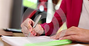 Closeup of businesswoman hands holding pen, makes notes in notebook and performs test task