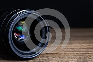 Closeup camera lens on a wooden floor with black dark background