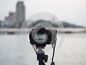 Closeup of a camera on a tripod outdoors. Background Landscape out of focus, select focus