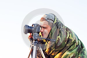 Closeup of a camouflaged paparazzi photographer taking picture