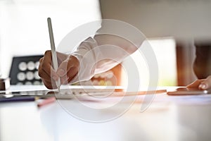 Closeup and candid photo of hands using digital pen on digital tablet computer on table