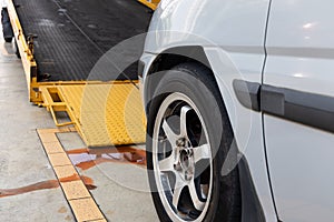 Closeup on car towed onto flatbed tow truck with cable