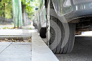 Closeup of a car wheel parked near curb on the side of the street on a parking lot