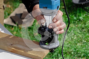 closeup of carpenter with hand wood router machine at work. closeup of routing a bevel into plank of pine woodworking