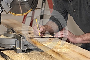 closeup of carpenter marking line on wooded board with pencil and wooden square during home remodel