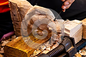 Closeup of a carpenter`s hands working with a chisel and hammer on wooden buddha sculpture