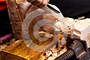 Closeup of a carpenter`s hands working with a chisel and hammer on wooden buddha sculpture