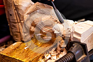 Closeup of a carpenter`s hands working with a chisel and hammer on wooden buddha sculpture