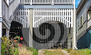 Closeup of carport-garage underneath a Queenslander house with white boards in an arch and divided driveway