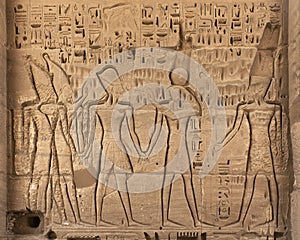 Closeup of a carved stone relief with Ramesses III being led by Ra before Amun in Medina Habu.