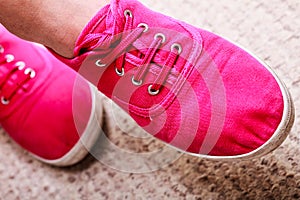 Closeup of casual vibrant pink sneakers shoes boots on female feet