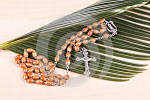 Closeup Catholic rosary with crucifix and beads on palm leaf